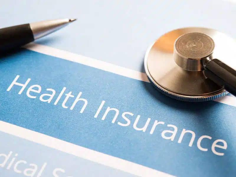 pen and stethoscope on top of a health insurance application page