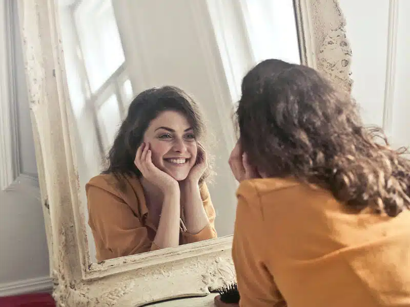 happy woman looking in the mirror after overcoming addiction